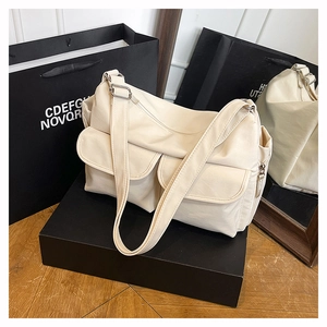Detail of off-white nylon crossbody bag showing dual front pockets and silver buckle