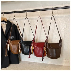 Detailansicht von vier Retro-Leder-Eimertaschen mit ethnischen Holzperlen-Quasten-Anhängern