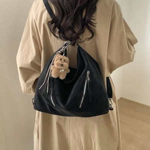 Rear view of large black suede hobo bag with silver zippers and plush dog charm accessory