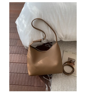Detailed view of brown litchi grain leather hobo bag with dual shoulder straps on a rug