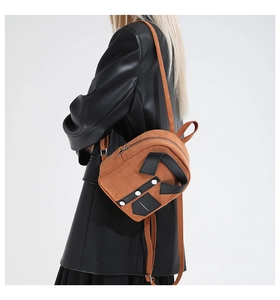 Close-up of brown suede backpack with rivet details on model in black leather jacket