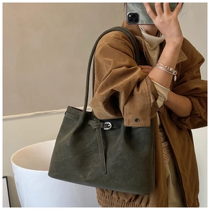 Detail of dark green matte suede tote bag featuring adjustable strap and silver metal buckle