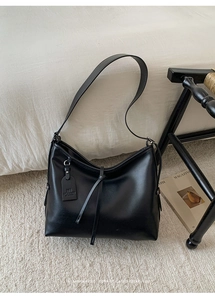 Gros plan du sac cabas en cuir noir avec étiquette logo sur une surface texturée