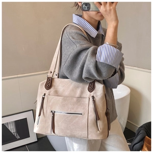 Détail d'un sac à bandoulière vintage beige avec lanières en cuir et poches zippées