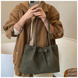 Detail view of olive green tote bag featuring matte texture and vintage leather strap buckle