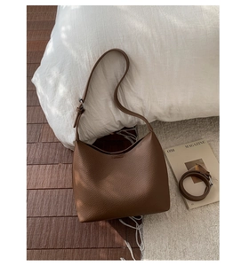 Detail of brown lychee grain leather bucket bag with adjustable wide and slim straps