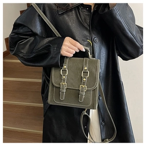 Detail of dark green vintage crossbody bag with white stitching and gold buckles