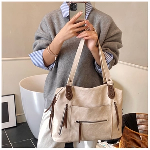 Détail du grand sac cabas en toile beige avec poignées en cuir marron et pompons frangés