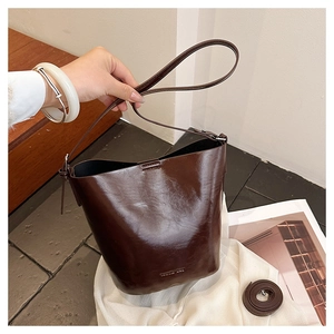 Detail view of a vintage dark brown glossy bucket bag with an adjustable shoulder strap