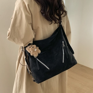 Close-up of black suede large capacity shoulder bag with metal zippers and bear charm