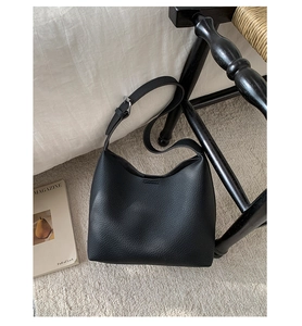 Close-up of black pebble grain leather shoulder bag shown in a cozy home setting