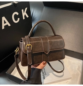 Dettaglio della borsa a tracolla vintage marrone scuro con fibbia dorata in confezione