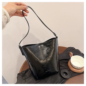 Macro detail of black vintage bucket bag featuring glossy leather texture and straps
