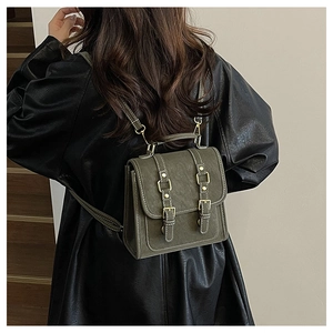 Close-up of olive green vintage backpack with metallic buckles on a model in leather jacket