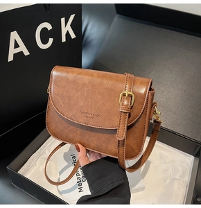 Detailed close-up of brown vintage leather crossbody bag in elegant gift box packaging