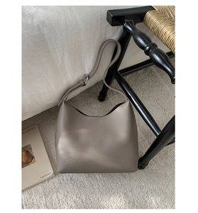 Close-up of taupe litchi grain leather texture and adjustable strap on a bucket bag
