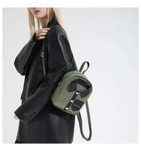 Detail of shirt-shaped mini backpack in army green with black collar and metal buttons