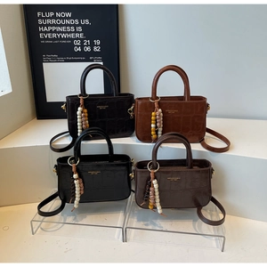 Detail of four vintage crocodile pattern handbags with wooden bead tassel ornaments
