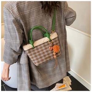 Détail du sac cabas à carreaux avec bordure en fourrure, anse en cuir vert et breloque