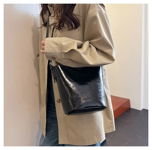 Close-up of black glossy patent leather bucket bag showing texture and sleek finish