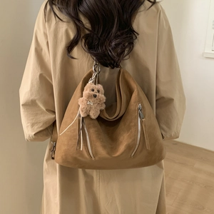 Brown suede hobo shoulder bag with silver zippers and plush bear charm on model
