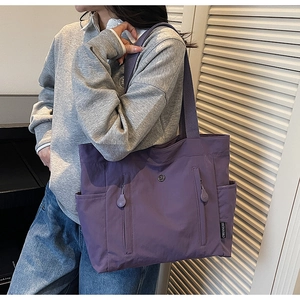 Detail of purple canvas tote bag with functional double zippers and side pockets on shoulder