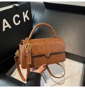 Dettaglio borsa marrone in PU con texture retrò, patta a V e dettagli in metallo dorato