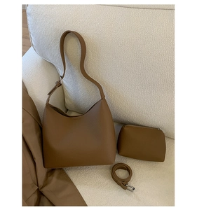 Brown lychee grain leather bucket bag set with matching small zipper pouch on beige sofa