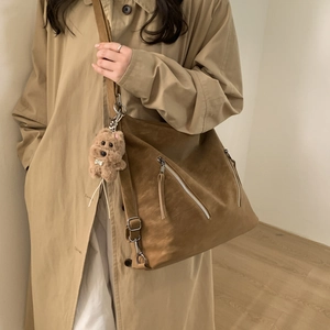 Detail of brown large-capacity crossbody bag with zippers and cute plush dog charm