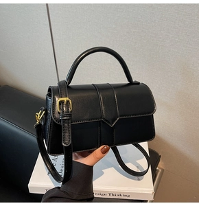 Dettaglio della borsa nera strutturata con cuciture verticali e fibbia in metallo dorato