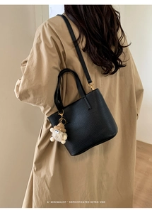 Rear view of model wearing a black lychee texture bucket bag with crochet charm detail