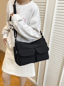 Minimalist black nylon crossbody bag with dual pockets and adjustable shoulder strap