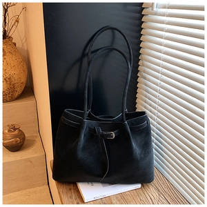 Detail of elegant black tote bag featuring metal buckle and premium suede texture