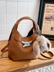 Brown litchi grain leather bucket bag with silver metal knot and bunny pendant accessory