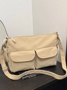 Minimalist beige nylon crossbody bag with dual front pockets and adjustable shoulder strap