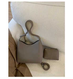 Detailed set of khaki bucket bag with matching pouch and strap on a neutral sofa