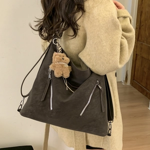 Detailed view of coffee brown faux leather tote bag with stylish plush bear charm detail