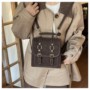 Detail of vintage dark brown leather backpack featuring gold buckles and adjustable straps