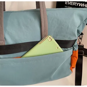 Dettaglio della tasca frontale di una borsa da viaggio blu con dentro un tablet