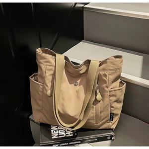Close-up of khaki nylon tote bag with side pockets on stairs for daily urban commute
