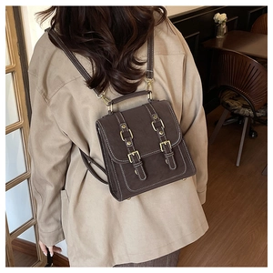 Close-up of vintage brown leather mini backpack with contrast stitching and metal buckles