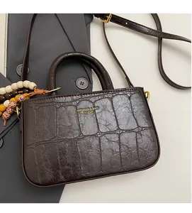 Detailed texture of dark brown crocodile pattern PU leather bag with beaded charm