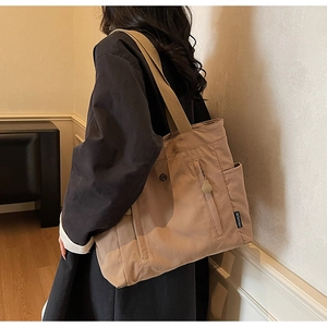 Detail of khaki canvas tote bag with side zipper pocket and branded woven label