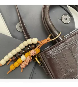 Close-up of retro colorful beaded wood charm attached to a brown faux leather handbag