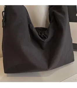 Detailed close-up of soft black nylon fabric and zipper pull on a stylish tote bag