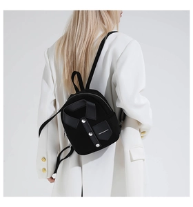 Detail of black mini backpack featuring shirt-collar design and silver metal buttons