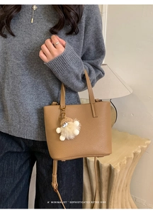Brown litchi grain leather bucket bag with plush charm and adjustable shoulder strap