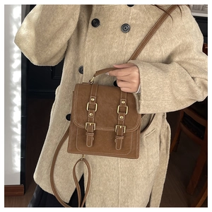 Close-up of vintage brown suede backpack with gold hardware and double-buckle closure