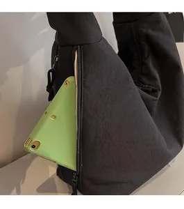 Detail of the side zipper pocket on a black canvas tote bag with a green tablet storage