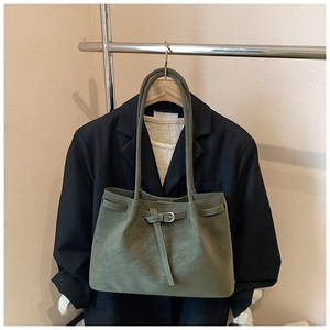Detailed view of olive green tote bag with matte texture and buckle strap on a hanger